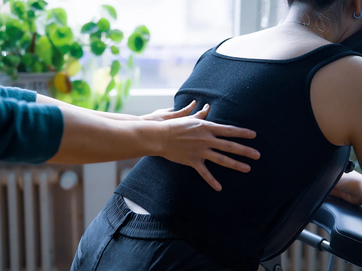 Shiatsu sur chaise en entreprise : Stéphanie Vuong travaille le méridien de la Vessie d'une collaboratrice assise sur une chaise ergonomique